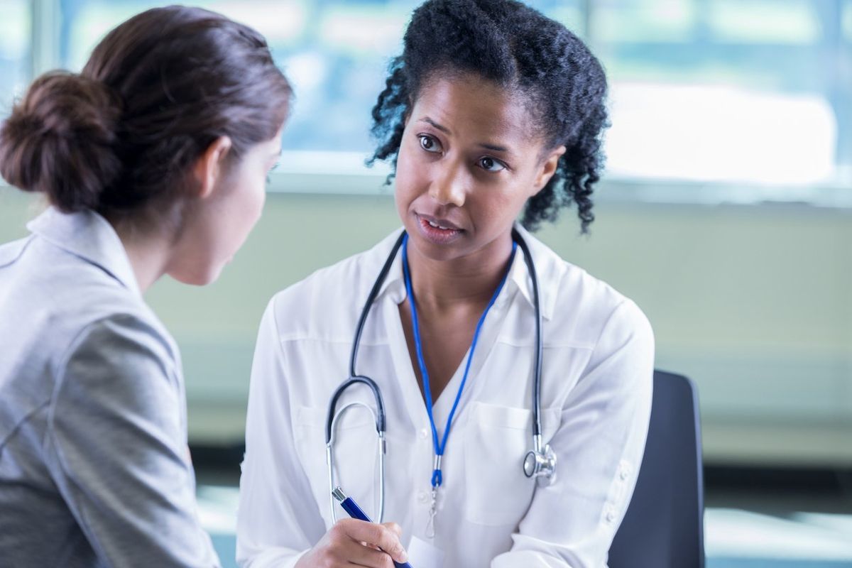 A compassionate female doctor sits across from a patient and listens to her story.