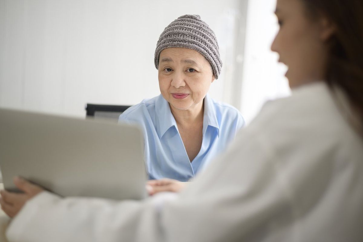 cancer patient woman wearing head scarf after chemotherapy consulting and visiting doctor in hospital