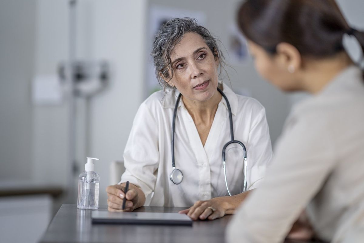 female doctor points to the screen of her tablet laying out on the table in front of her as she shares her patients test results with her