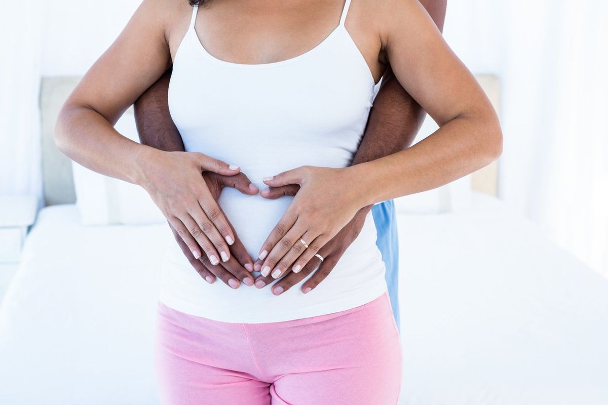 Midsection of couple hands making heart shape on belly