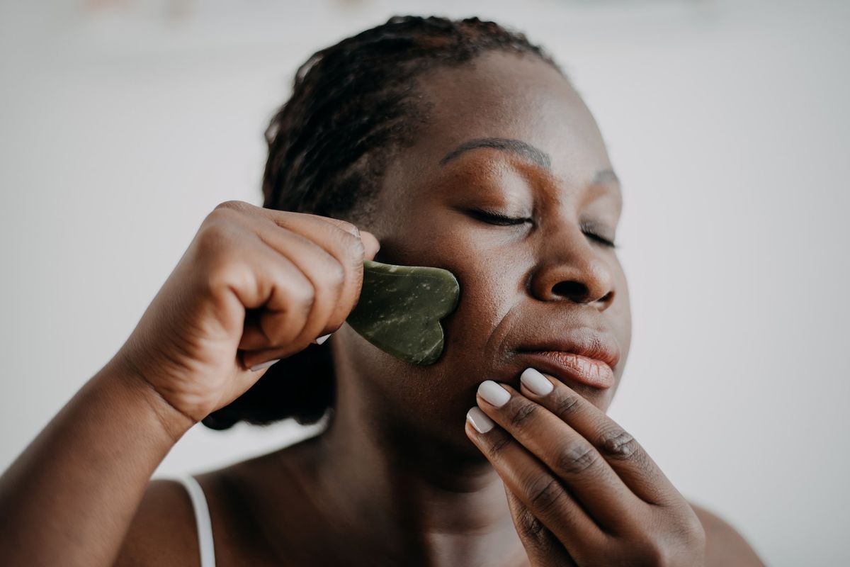 woman doing gua sha on her face